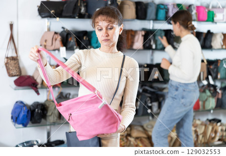 Middle-aged woman choosing handbag in clothing store 129032553