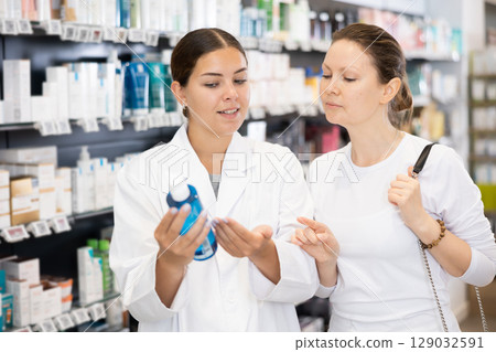 Woman pharmacist helping woman customer to choose cosmetic product 129032591