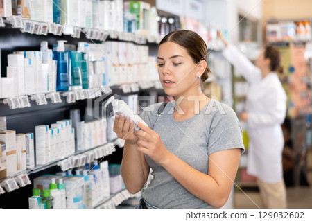 Young woman chooses cosmetic product in pharmacy 129032602
