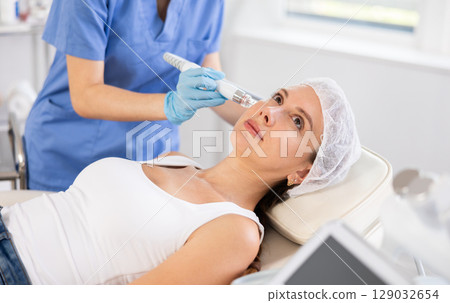 Young woman getting cosmetic facial procedure using ion bubble pen Young woman getting cosmetic facial procedure using ion bubble pen 129032654