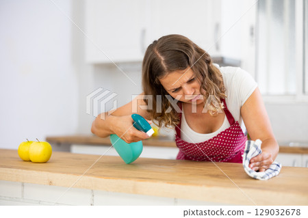 Focused young girl housewife cleaning table Focused young girl housewife cleaning table 129032678