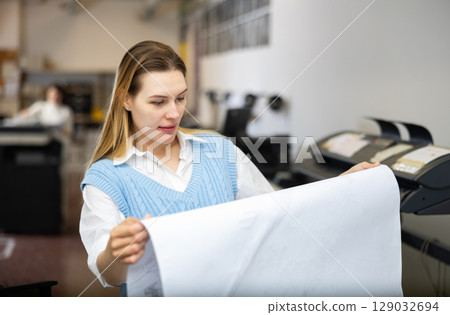 Printing establishment worker examining large piece of paper Printing establishment worker examining large piece of paper 129032694