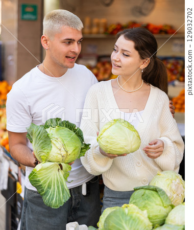 Married couple near vegetable stand in store choose cabbage 129032702