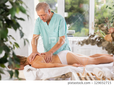 male masseur giving massage to female patient 129032715