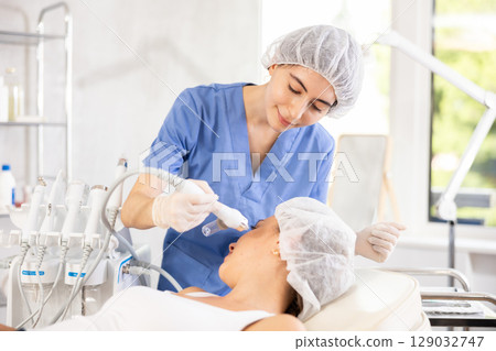 Female aesthetician applying atomized nutrients onto woman client face 129032747