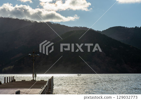 冬日的蘆之湖，在逆光下閃閃發光。湖畔的棧橋和波光粼粼的水面。 129032773