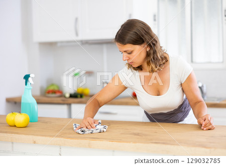 Focused young girl housewife cleaning table Focused young girl housewife cleaning table 129032785