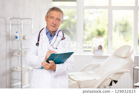 Senior medical specialist gets acquainted reads documents information about client of clinic Senior medical specialist gets acquainted reads documents information about client of clinic 129032815