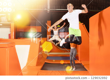 Joyful carefree young man leaping at trampoline park 129032892