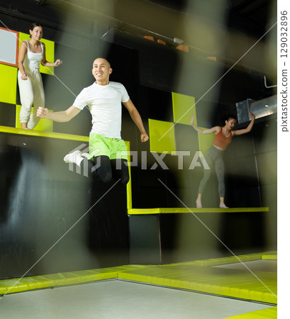 Emotional man jumping vertical and flying in trampoline sport center indoors 129032896