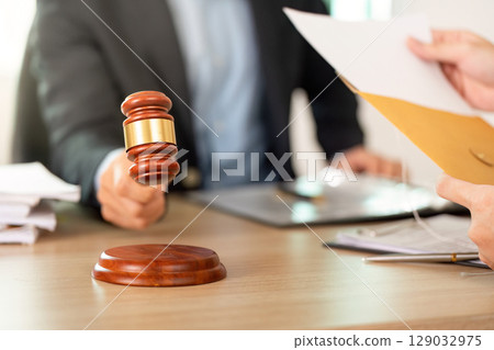 Court Proceedings. Lawyer presenting evidence with a gavel in the foreground. Court Proceedings. Lawyer presenting evidence with a gavel in the foreground. 129032975