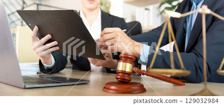 Legal Consultation. Lawyer and client reviewing documents with gavel in view. 129032984