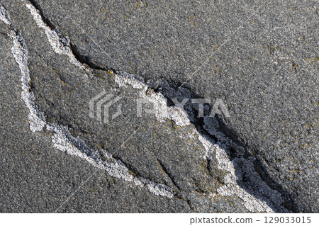 Detailed view of a rough stone surface with lichen in a crack 129033015