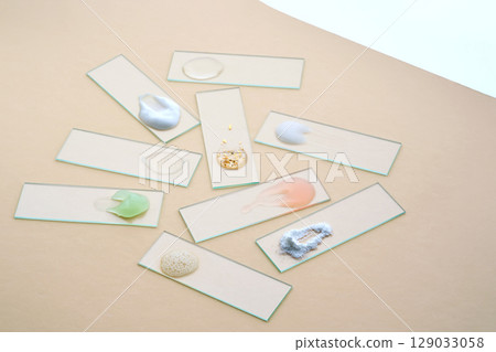 Samples of textures of various cosmetic products on a beige background. 129033058