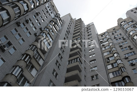 Facade of a budget high-rise building made of white brick with small apartments view from ground Facade of a budget high-rise building made of white brick with small apartments view from ground 129033067