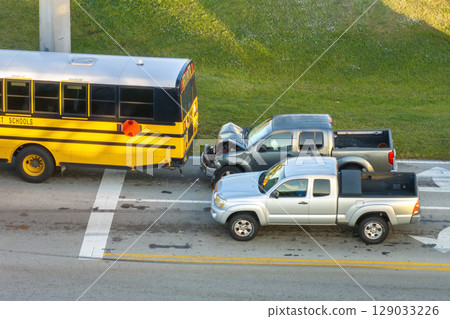 Traffic accident on American street in Florida. First responders helping victims of school bus and car crash on road in USA. Aerial view of emergency services responding to accident site 129033226