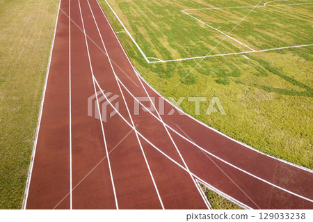 Top view of red running tracks and green grass lawn. Infrastructure for sports activities. Top view of red running tracks and green grass lawn. Infrastructure for sports activities. 129033238
