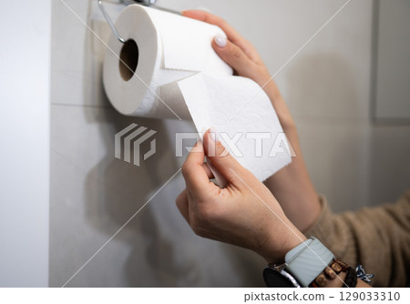 Female Hands Tear Off A Piece Of Toilet Paper 129033310