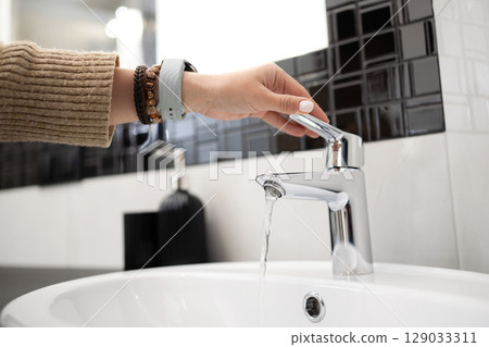 Girl Opens The Mixer Tap Of The Sink In The Bathroom Girl Opens The Mixer Tap Of The Sink In The Bathroom 129033311