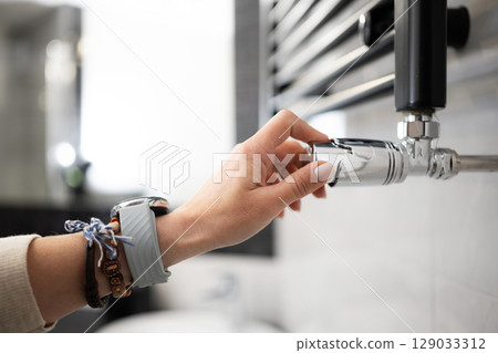 Female Hand Adjusting The Temperature Of The Radiator 129033312
