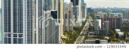 Sunny Isles Beach city with luxurious highrise hotels and condo buildings and busy ocean drive on Atlantic coast. American tourism infrastructure in southern Florida Sunny Isles Beach city with luxurious highrise hotels and condo buildings and busy ocean drive on Atlantic coast. American tourism infrastructure in southern Florida 129033349