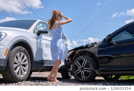 Stressed woman driver standing on street side shocked after car accident. Road safety and insurance concept 129033354