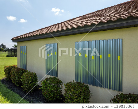 Storm shutters mounted on Florida house windows for hurricane protection. Preparing for natural disaster Storm shutters mounted on Florida house windows for hurricane protection. Preparing for natural disaster 129033365