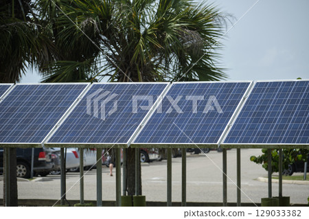Solar panels installed on stand frame near parking lot for effective generation of clean electricity. Photovoltaic technology integrated in urban infrastructure for electric car charging 129033382
