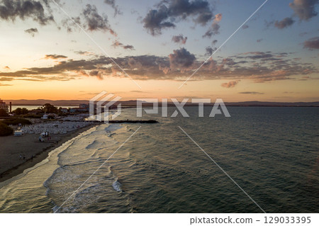 Sea surface with blue water waves under yellow and purple sunset sky. 129033395