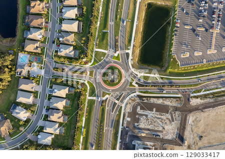 Roundabout crossroads on American city street with moving traffic cars. Circular transportation crossroads in USA Roundabout crossroads on American city street with moving traffic cars. Circular transportation crossroads in USA 129033417