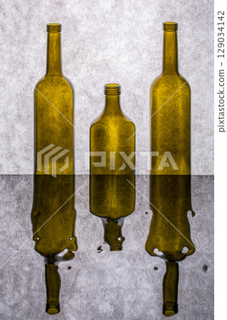 Still life with colored bottles on a reflective surface Still life with colored bottles on a reflective surface 129034142