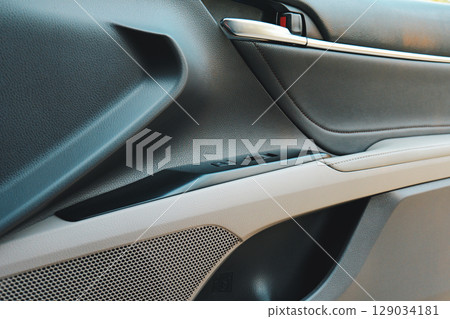 Close up view of a car's door panel highlighting controls and materials used 129034181