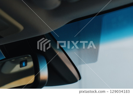 Detailed examination of a car's interior, highlighting the windshield area and mirror Detailed examination of a car's interior, highlighting the windshield area and mirror 129034183
