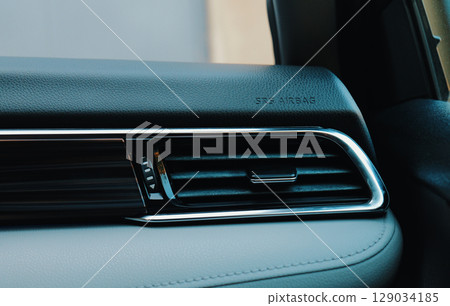 Close up view of a sleek car dashboard showing airbag indicator and ventilation 129034185