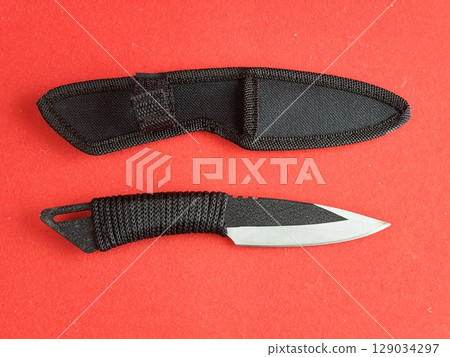 Throwing knife scorpion and black case. Traditional Japanese cold weapon on a red background. 129034297