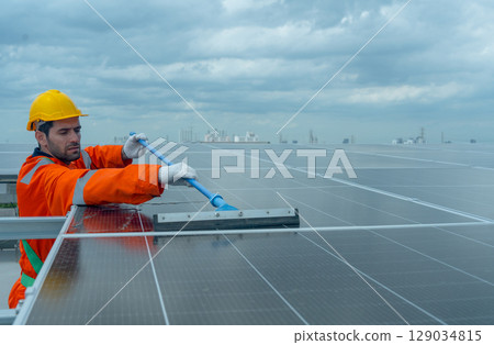 Front view profession engineer or technician worker use cleaning brush to clean solarcell panel in area of rooftop of building. Front view profession engineer or technician worker use cleaning brush to clean solarcell panel in area of rooftop of building. 129034815