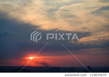 Colorful sunset sky with soft clouds and city horizon. 129034870