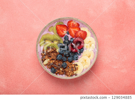Delicious acai bowl with fresh fruits and granola in white ceramic bowl on pink table top view, healthy breakfast or snack Delicious acai bowl with fresh fruits and granola in white ceramic bowl on pink table top view, healthy breakfast or snack 129034885