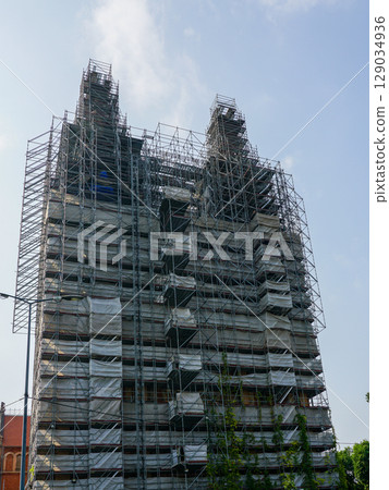 Historic Cathedral Under Restoration Wrapped in Dense Metal Scaffolding and Safety Netting 129034936