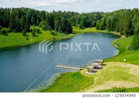 Peaceful Lakeside Landscape with Wooden Shelters and Dock in Stanczyki, Poland on a Summer Day Peaceful Lakeside Landscape with Wooden Shelters and Dock in Stanczyki, Poland on a Summer Day 129034948