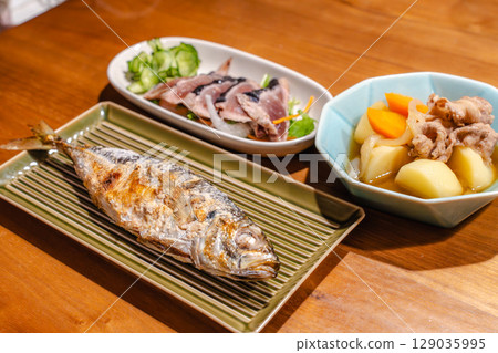 A dinner table with grilled fish, meat and potato stew, and seared bonito 129035995