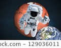 An astronaut floats in deep space, framed by the reddish sphere of Mars above and the blue Earth below. The space suit is detailed, helmet visor reflective, and instruments visible. Stars fill the 129036011