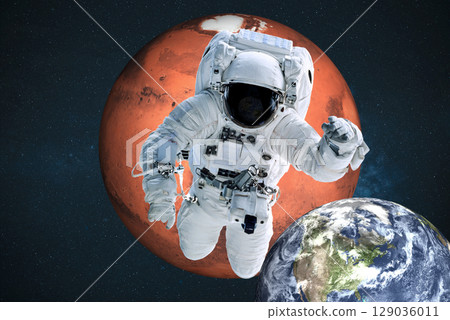 An astronaut floats in deep space, framed by the reddish sphere of Mars above and the blue Earth below. The space suit is detailed, helmet visor reflective, and instruments visible. Stars fill the 129036011