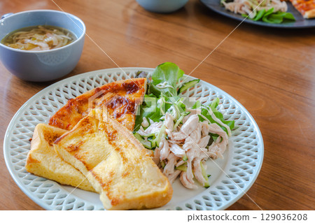 A breakfast plate featuring French toast, salad chicken, and pizza A breakfast plate featuring French toast, salad chicken, and pizza 129036208