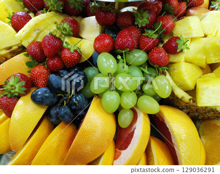 assorted ripe fruits and berries on a white plate 129036291