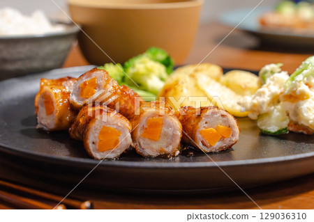 Dinner plate with pork wrapped in carrots and side dishes 129036310