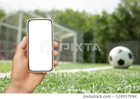 Man use mobile phone. of football on field as background Man use mobile phone. of football on field as background 129037094