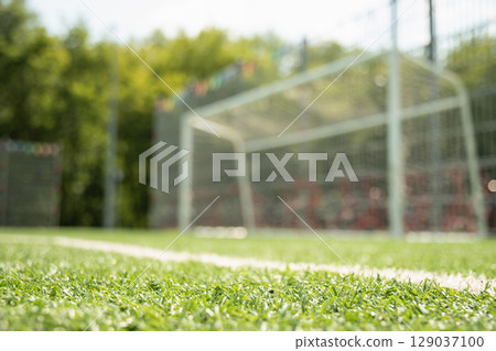 Empty soccer goal on field with artificial green grass. Summer outdoor game. 129037100