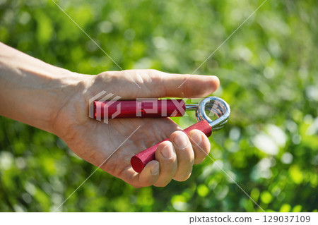 Sports red metal expander in man's hand. 129037109