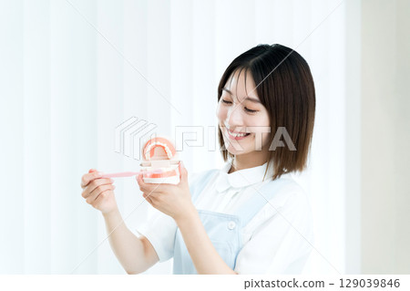Dental staff woman holding a toothbrush and a tooth model 129039846